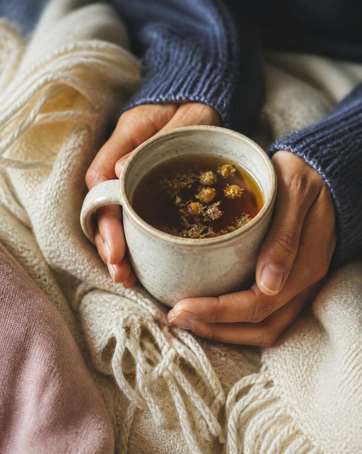 Hands holding a warm cup of herbal tea